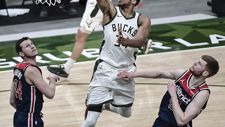 May 5, 2021; Milwaukee, Wisconsin, USA; Milwaukee Bucks forward Giannis Antetokounmpo (34) scores a basket against Washington Wizards guard Garrison Mathews (24) and forward Davis Bertans (42) in the fourth quarter at Fiserv Forum. Mandatory Credit: Benny Sieu-USA TODAY Sports