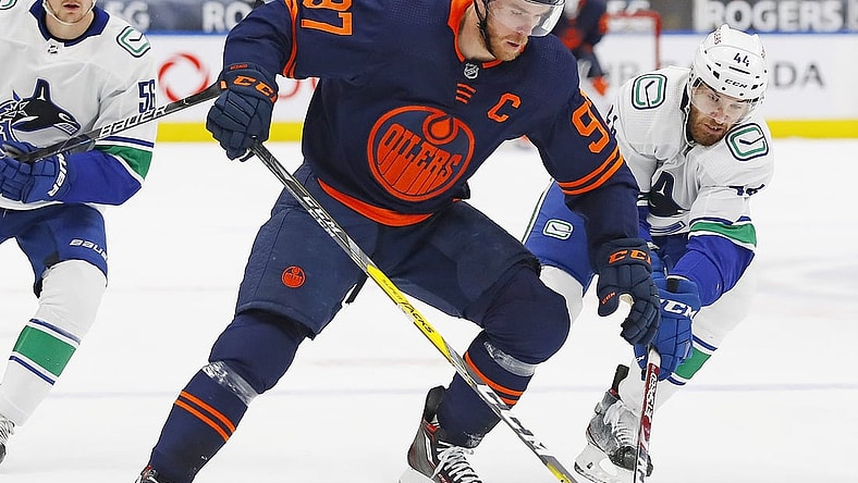 May 8, 2021; Edmonton, Alberta, CAN; Edmonton Oilers forward Connor McDavid (97) battle for the puck against Vancouver Canucks forward Tyler Graovac (44) during the first period at Rogers Place. Mandatory Credit: Perry Nelson-USA TODAY Sports