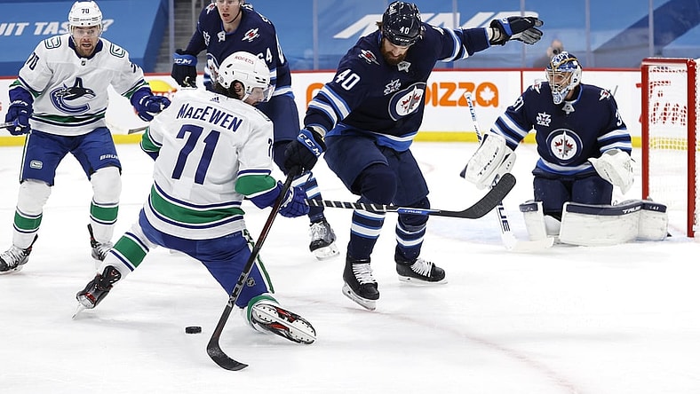 May 11, 2021; Winnipeg, Manitoba, CAN; Vancouver Canucks center Zack MacEwen (71) and Winnipeg Jets defenseman Jordie Benn (40) battle for the puck during the first period at Bell MTS Place. Mandatory Credit: James Carey Lauder-USA TODAY Sports
