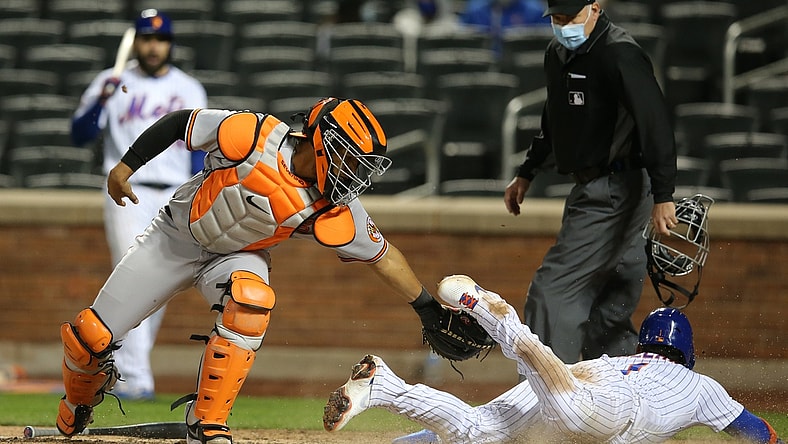May 11, 2021; New York City, New York, USA; New York Mets third baseman Jonathan Villar (R) scores a run ahead of the tag of Baltimore Orioles catcher Pedro Severino (L) on a hit by Mets pinch hitter Patrick Mazeika (not pictured) during the ninth inning at Citi Field. Mandatory Credit: Brad Penner-USA TODAY Sports