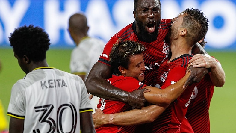 May 12, 2021; Orlando, Florida, CAN; Toronto FC forward Jozy Altidore (top) celebrates with forward Tsubasa Endoh (31) and defender Omar Gonzalez (right) after scoring a goal during the second half against Columbus Crew FC at Orlando City Stadium. Mandatory Credit: Nathan Ray Seebeck-USA TODAY Sports