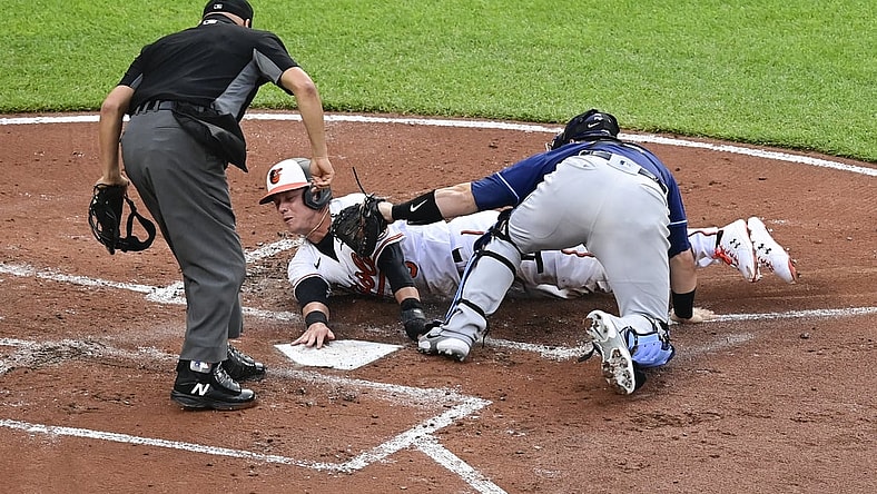 May 19, 2021; Baltimore, Maryland, USA;  Home plate umpire Vic Carapazza (19) signals Tampa Bay Rays catcher Mike Zunino (10) tags out Baltimore Orioles third baseman Ryan Mountcastle (6) at the plate during the second inning at Oriole Park at Camden Yards. Mandatory Credit: Tommy Gilligan-USA TODAY Sports