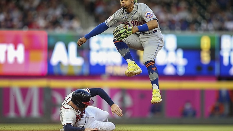 May 19, 2021; Atlanta, Georgia, USA; New York Mets shortstop Francisco Lindor (12) turns a double play over Atlanta Braves first baseman Freddie Freeman (5) in the fourth inning at Truist Park. Mandatory Credit: Brett Davis-USA TODAY Sports