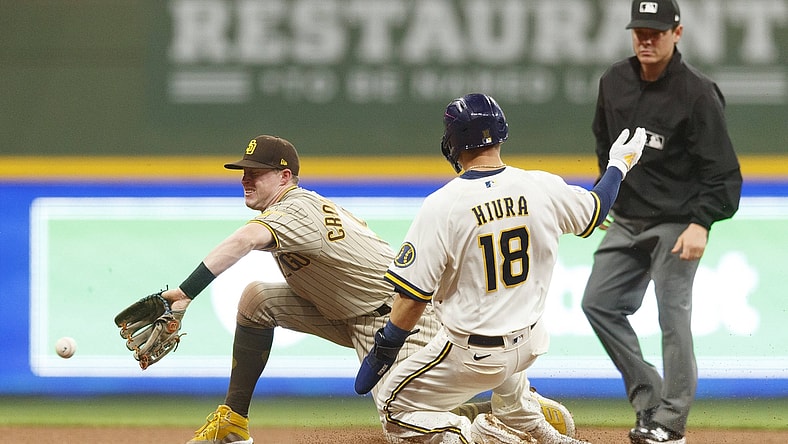 May 24, 2021; Milwaukee, Wisconsin, USA;  Milwaukee Brewers first baseman Keston Hiura (18) takes second base on a wild pitch as San Diego Padres second baseman Jake Cronenworth (9) takes the throw during the fourth inning at American Family Field. Mandatory Credit: Jeff Hanisch-USA TODAY Sports