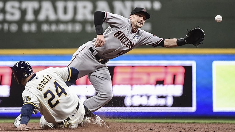 Jun 3, 2021; Milwaukee, Wisconsin, USA;  Arizona Diamondbacks shortstop Nick Ahmed (13) reaches for ball on a throwing error by first baseman Christian Walker (not pictured) as Milwaukee Brewers center fielder Avisail Garcia (24) slides advances in the fifth inning at American Family Field. Mandatory Credit: Benny Sieu-USA TODAY Sports