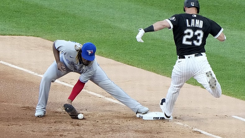 Jun 9, 2021; Chicago, Illinois, USA; Toronto Blue Jays designated hitter Vladimir Guerrero Jr. (27) drops the ball making Chicago White Sox third baseman Jake Lamb (23) safe at first on an error during the first inning at Guaranteed Rate Field. Mandatory Credit: Mike Dinovo-USA TODAY Sports
