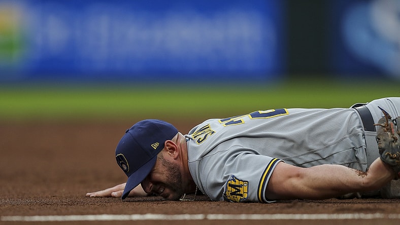 Jun 9, 2021; Cincinnati, Ohio, USA; Milwaukee Brewers third baseman Travis Shaw (21) falls and is injured after attempting to catch a ground ball against the Cincinnati Reds in the second inning at Great American Ball Park. Mandatory Credit: Katie Stratman-USA TODAY Sports