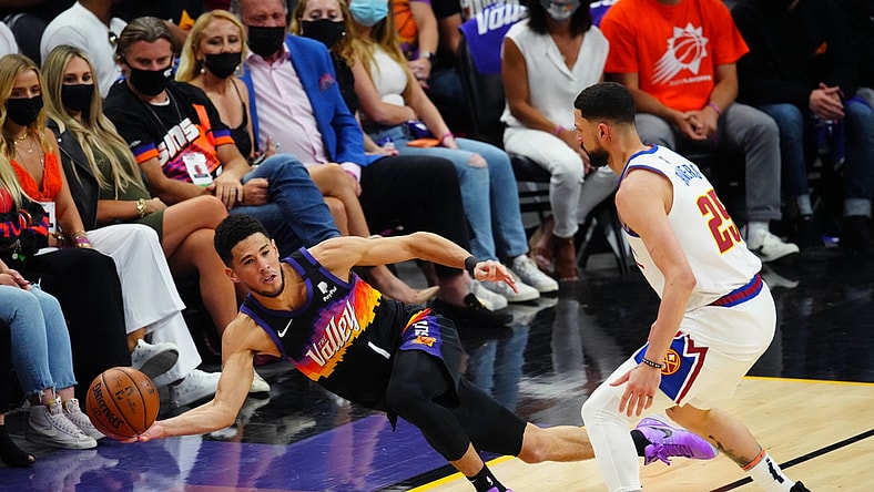 Jun 9, 2021; Phoenix, Arizona, USA; Phoenix Suns guard Devin Booker (1) passes the ball as he dives to save it from going out of bounds against Denver Nuggets guard Austin Rivers in the first half during game two in the second round of the 2021 NBA Playoffs at Phoenix Suns Arena. Mandatory Credit: Mark J. Rebilas-USA TODAY Sports