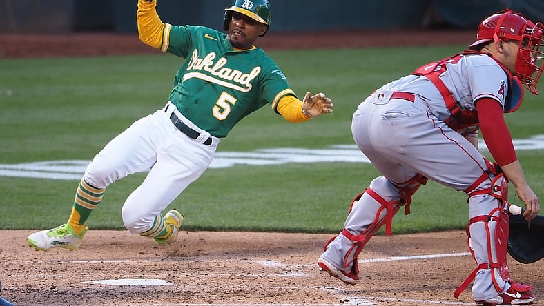 Jun 14, 2021; Oakland, California, USA; Oakland Athletics left fielder Tony Kemp (5) slides safely home behind Los Angeles Angels catcher Max Stassi (33) during the third inning at RingCentral Coliseum. Mandatory Credit: Kelley L Cox-USA TODAY Sports