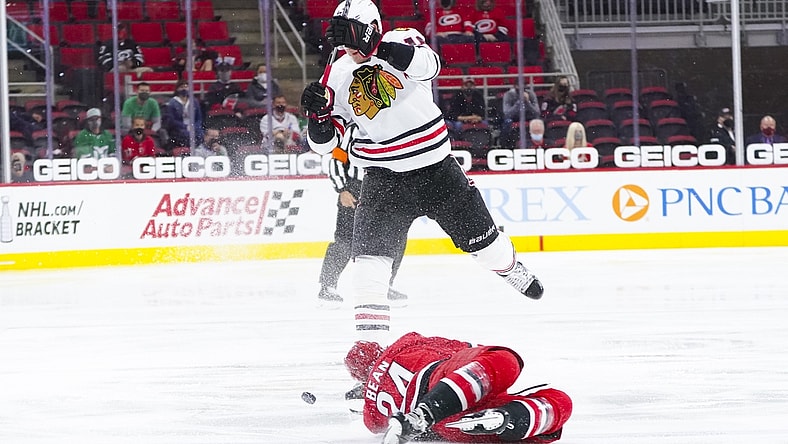 May 6, 2021; Raleigh, North Carolina, USA;  Carolina Hurricanes defenseman Jake Bean (24) dives to the ice to avoid the check by Chicago Blackhawks defenseman Nikita Zadorov (16) during the third period at PNC Arena. Mandatory Credit: James Guillory-USA TODAY Sports