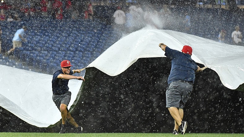 Jun 30, 2021; Philadelphia, Pennsylvania, USA; Members of the Philadelphia Phillies Grounds Crew pull the tarp over the infield during a rain delay in the fifth inning against the Miami Marlins at Citizens Bank Park. Mandatory Credit: Eric Hartline-USA TODAY Sports