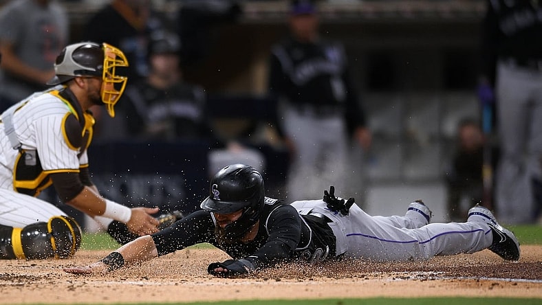 Jul 9, 2021; San Diego, California, USA; Colorado Rockies right fielder Chris Owings (right) slides home to score a run on a double hit by starting pitcher Kyle Freeland (not pictured) during the fourth inning against the San Diego Padres at Petco Park. Mandatory Credit: Orlando Ramirez-USA TODAY Sports