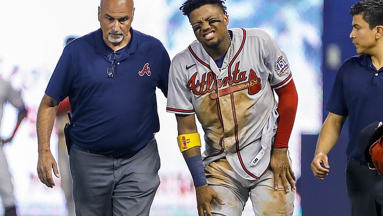 Jul 10, 2021; Miami, Florida, USA; Atlanta Braves right fielder Ronald Acuna Jr. (13) reacts as he gets taken off the field by training staff after an apparent leg injury during the fifth inning  against the Miami Marlins at loanDepot Park. Mandatory Credit: Sam Navarro-USA TODAY Sports