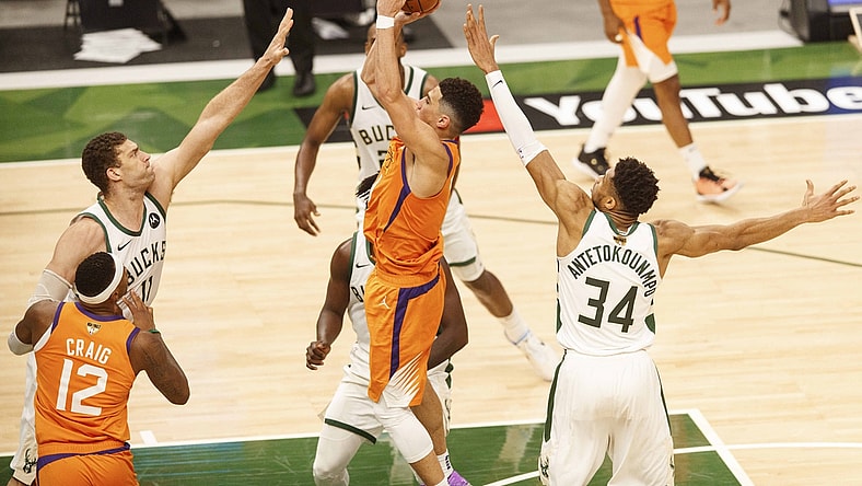 Jul 14, 2021; Milwaukee, Wisconsin, USA; Phoenix Suns guard Devin Booker (1) shoots between Milwaukee Bucks center Brook Lopez (11) and forward Giannis Antetokounmpo (34) during the third quarter during game four of the 2021 NBA Finals at Fiserv Forum. Mandatory Credit: Jeff Hanisch-USA TODAY Sports