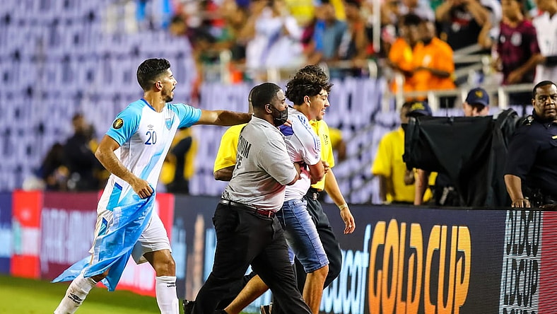 Jul 14, 2021; Dallas, Texas, USA; Guatemala defender Gerardo Gordillo (20) hands a flag back to a fan who ran onto the field during the second half of CONCACAF Gold Cup Soccer group stage play at Cotton Bowl. Mandatory Credit: Ben Ludeman-USA TODAY Sports