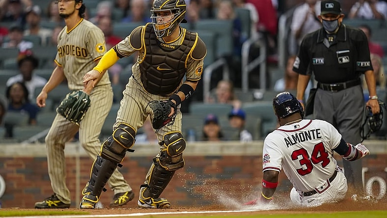 Jul 20, 2021; Cumberland, Georgia, USA; Atlanta Braves left fielder Abraham Almonte (34) scores a run behind San Diego Padres catcher Victor Caratini (17) during the second inning at Truist Park. Mandatory Credit: Dale Zanine-USA TODAY Sports