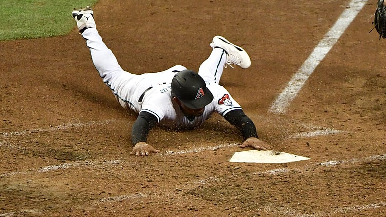 Jul 20, 2021; Phoenix, Arizona, USA;  Arizona Diamondbacks third baseman Eduardo Escobar (5) slides into home plate to score in the sixth inning against the Pittsburgh Pirates at Chase Field. Mandatory Credit: Matt Kartozian-USA TODAY Sports