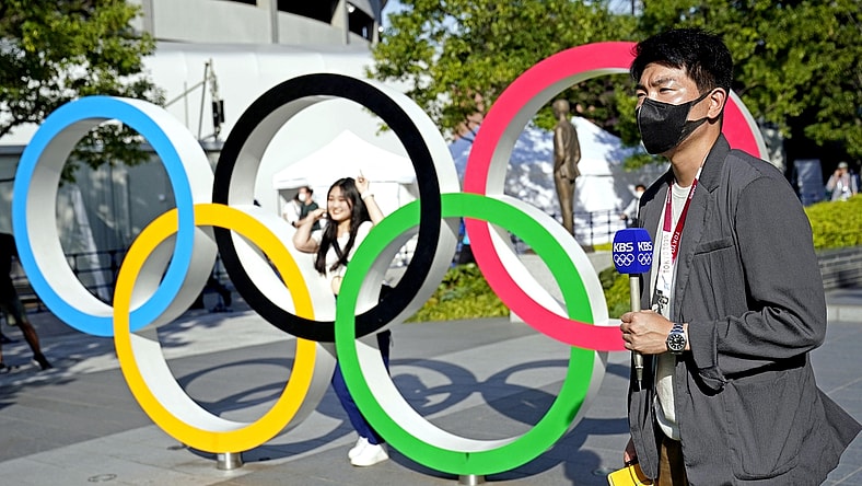 Jul 21, 2021; Tokyo, Japan; A reporter from KBS reports in front of the Olympic Rings outside the Olympic Stadium before the Tokyo 2020 Summer Olympic Games. Mandatory Credit: Michael Madrid-USA TODAY Network