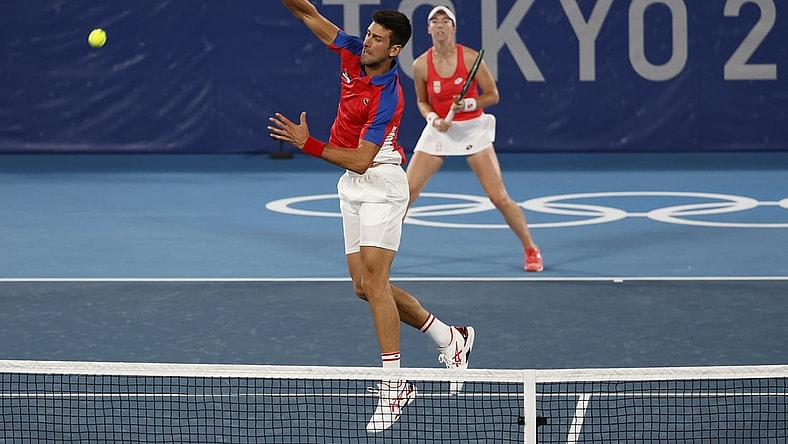 Jul 28, 2021; Tokyo, Japan; Novak Djokovic (L) leaps to hit an overhead in front of partner Nina Stajanovic (R) (both of Serbia) against Marcelo Melo and Luisa Stefari (both of Brazil, not pictured) in a first round mixed doubles match during the Tokyo 2020 Olympic Summer Games at Ariake Tennis Park. Mandatory Credit: Geoff Burke-USA TODAY Sports
