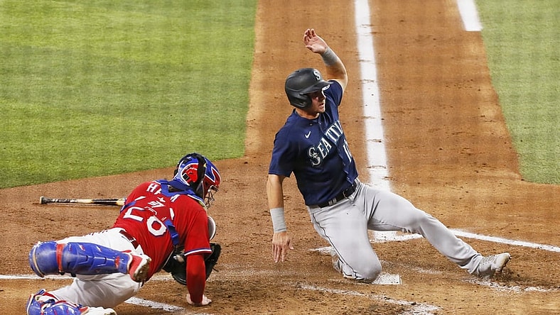 Jul 30, 2021; Arlington, Texas, USA; Seattle Mariners center fielder Jarred Kelenic (10) slides home past Texas Rangers catcher Jonah Heim (28) to score a run during the second inning at Globe Life Field. Mandatory Credit: Raymond Carlin III-USA TODAY Sports