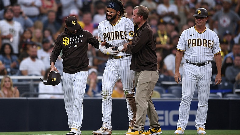 Jul 30, 2021; San Diego, California, USA; San Diego Padres shortstop Fernando Tatis Jr. (second from left) is helped off the field by manager Jayce Tingler (left) and a trainer after an injury during the first inning against the Colorado Rockies at Petco Park. Mandatory Credit: Orlando Ramirez-USA TODAY Sports