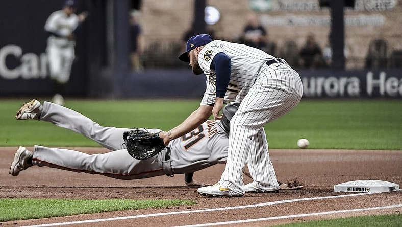 Aug 6, 2021; Milwaukee, Wisconsin, USA; Milwaukee Brewers first baseman Rowdy Tellez (11) cannot field the ball on a throwing error by pitcher Corbin Burnes (not pictured) while trying to pick off San Francisco Giants center fielder LaMonte Wade Jr (31) in the first inning at American Family Field. Mandatory Credit: Benny Sieu-USA TODAY Sports