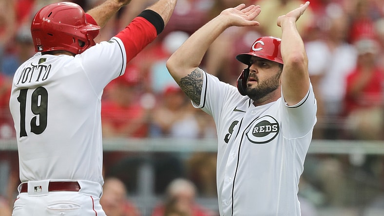 Aug 6, 2021; Cincinnati, Ohio, USA; Cincinnati Reds third baseman Mike Moustakas (right) reacts with first baseman Joey Votto (19) after scoring against the Pittsburgh Pirates during the first inning at Great American Ball Park. Mandatory Credit: David Kohl-USA TODAY Sports