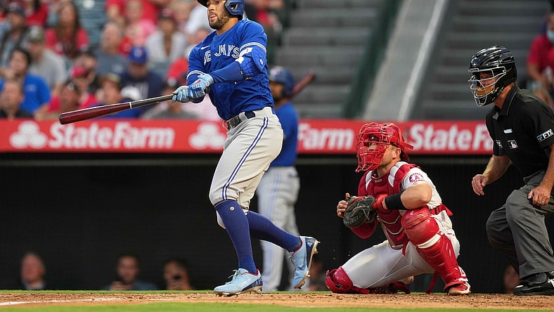 Aug 11, 2021; Anaheim, California, USA; Toronto Blue Jays center fielder George Springer (4) follows through on a solo home run in the second inning as Los Angeles Angels catcher Max Stassi (33) and umpire Ed Hickox (15) watch at Angel Stadium. Mandatory Credit: Kirby Lee-USA TODAY Sports