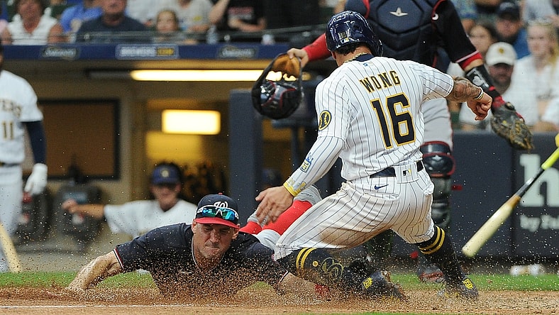 Aug 21, 2021; Milwaukee, Wisconsin, USA;  Washington Nationals first baseman Ryan Zimmerman (11) races to tag out Milwaukee Brewers second baseman Kolten Wong (16) at home plate in the fifth inning at American Family Field. Mandatory Credit: Michael McLoone-USA TODAY Sports