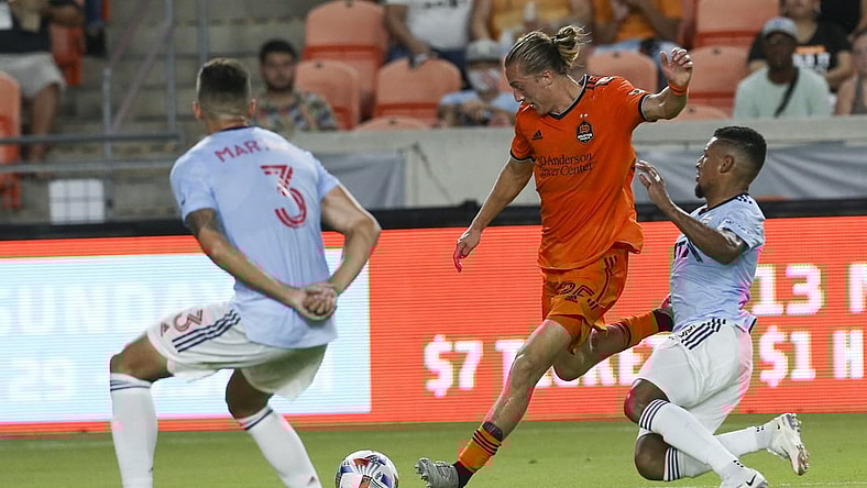 Aug 21, 2021; Houston, Texas, USA; Houston Dynamo midfielder Griffin Dorsey (25) splits the FC Dallas midfielder Bryan Acosta (8) and defender Jose Antonio Martinez (3)in the first half at BBVA Compass Stadium. Mandatory Credit: Thomas Shea-USA TODAY Sports