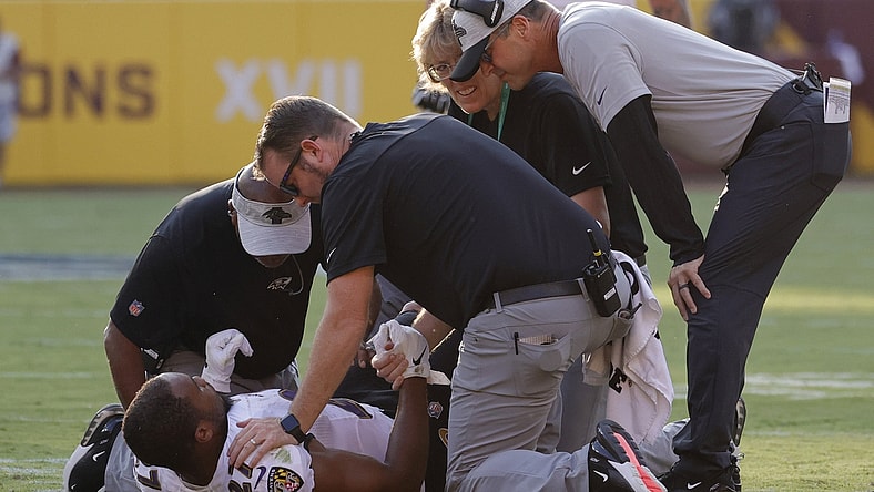 Aug 28, 2021; Landover, Maryland, USA; Baltimore Ravens head coach John Harbaugh (R) looks on as team medical personnel help Ravens running back J.K. Dobbins (27) after being injured against the Washington Football Team in the first quarter at FedExField. Mandatory Credit: Geoff Burke-USA TODAY Sports