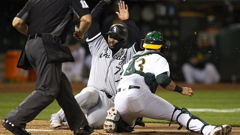 Sep 7, 2021; Oakland, California, USA; Chicago White Sox left fielder Eloy Jimenez (74) scores ahead of the tag by Oakland Athletics catcher Yan Gomes (23) on a single by Gavin Sheets during the fifth inning at RingCentral Coliseum. Umpire is Jeremy Riggs. Mandatory Credit: D. Ross Cameron-USA TODAY Sports