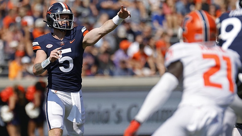 Sep 11, 2021; Charlottesville, Virginia, USA; Virginia Cavaliers quarterback Brennan Armstrong (5) passes the ball as Illinois Fighting Illini defensive back Jartavius Martin (21) watches in the first quarter at Scott Stadium. Mandatory Credit: Geoff Burke-USA TODAY Sports