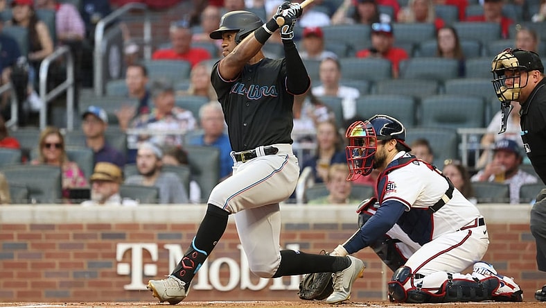 Sep 11, 2021; Atlanta, Georgia, USA; Miami Marlins outfielder Bryan De La Cruz (77) hits an RBI single scoring shortstop Miguel Rojas (not pictured) next to Atlanta Braves catcher Travis d'Arnaud (16) during the first inning at Truist Park. Mandatory Credit: Jason Getz-USA TODAY Sports