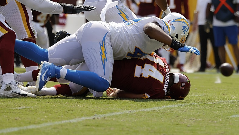 Sep 12, 2021; Landover, Maryland, USA; Washington Football Team quarterback Ryan Fitzpatrick (14) fumbles the ball after being hit by Los Angeles Chargers linebacker Uchenna Nwosu (42) while passing the ball in the second quarter at FedExField. Mandatory Credit: Geoff Burke-USA TODAY Sports
