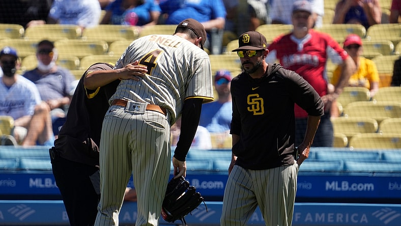 Sep 12, 2021; Los Angeles, California, USA; San Diego Padres starting pitcher Blake Snell (4) is helped off the field by a team trainer after apparently injuring himself throwing a pitch in the first inning against the Los Angeles Dodgers at Dodger Stadium. Mandatory Credit: Robert Hanashiro-USA TODAY Sports