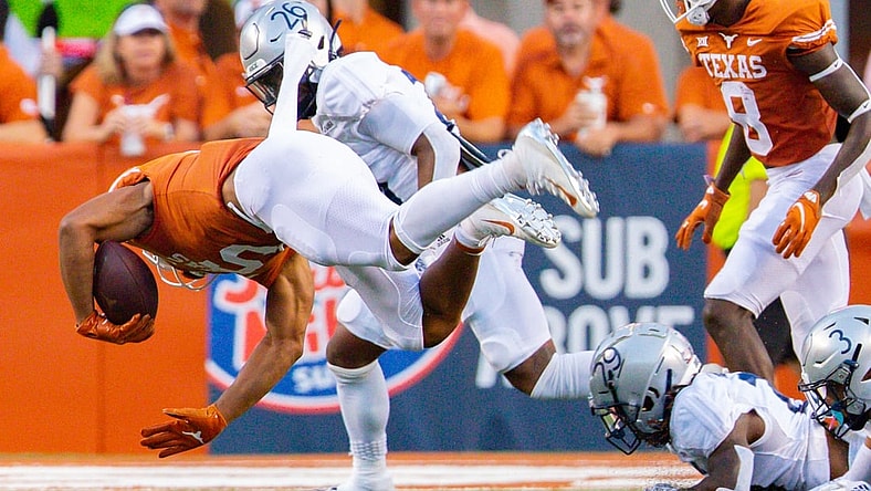 Sep 18, 2021; Austin, Texas; Texas Longhorns running back Bijan Robinson (5) goes airborne after being tripped up by Rice Owl defenders during the first quarter at Darrell K Royal-Texas Memorial Stadium. Mandatory Credit: John Gutierrez-USA TODAY Sports