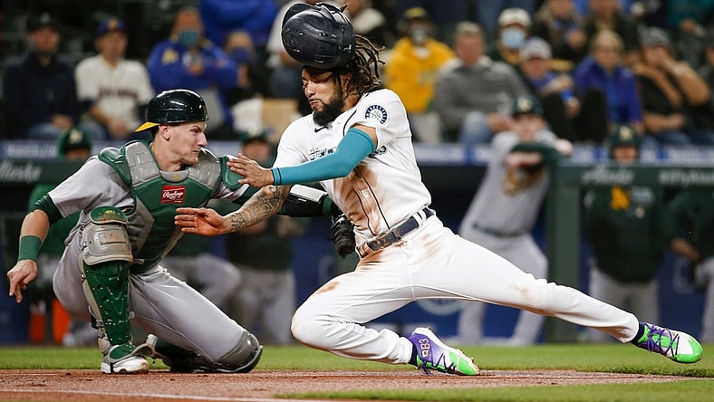 Sep 28, 2021; Seattle, Washington, USA; Oakland Athletics catcher Sean Murphy (12) tags out Seattle Mariners shortstop J.P. Crawford (right) as Crawford attempts to score from third base on a sacrifice fly during the first inning at T-Mobile Park. Mandatory Credit: Joe Nicholson-USA TODAY Sports