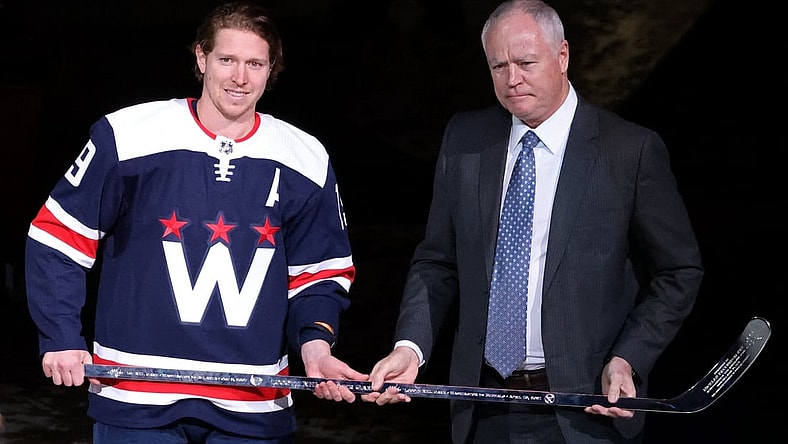 Apr 15, 2021; Washington, District of Columbia, USA; Washington Capitals center Nicklas Backstrom (19) is presented with a silver stick by Capitals' general manager Brian MacClellan (R) during a ceremony in recognition of Backstrom's 1,000th NHL game before the Capitals' game against the Buffalo Sabres at Capital One Arena. Mandatory Credit: Geoff Burke-USA TODAY Sports
