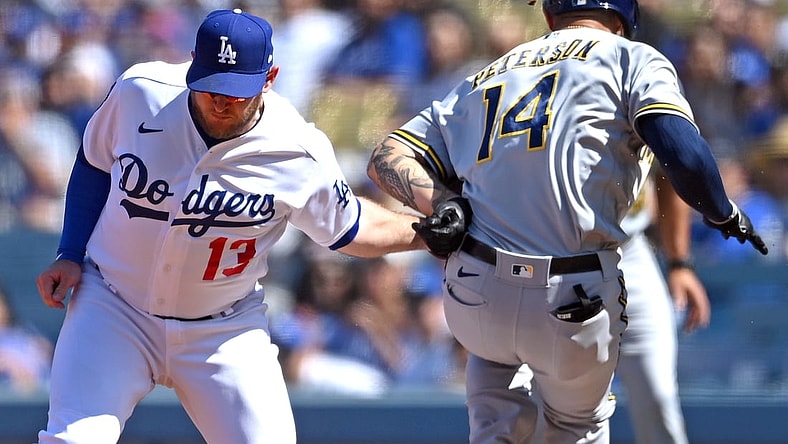 Oct 3, 2021; Los Angeles, California, USA;  Los Angeles Dodgers first baseman Max Muncy (13) injured his left arm as he made a tag on Milwaukee Brewers second baseman Jace Peterson (14) off a throw from Los Angeles Dodgers shortstop Trea Turner (6) in the third inning of the game at Dodger Stadium. Muncy left the game. Mandatory Credit: Jayne Kamin-Oncea-USA TODAY Sports