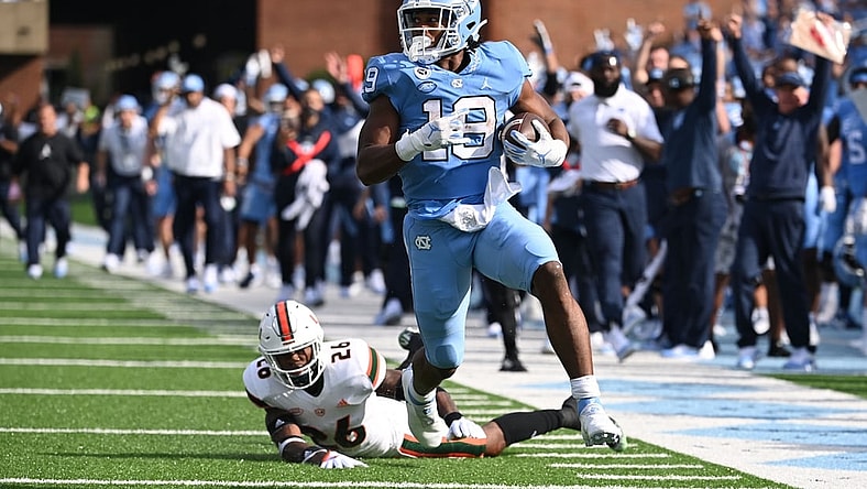 Oct 16, 2021; Chapel Hill, North Carolina, USA;  North Carolina Tar Heels running back Ty Chandler (19) runs for a touchdown as Miami Hurricanes safety Gurvan Hall Jr. (26) defends in the first quarter at Kenan Memorial Stadium. Mandatory Credit: Bob Donnan-USA TODAY Sports