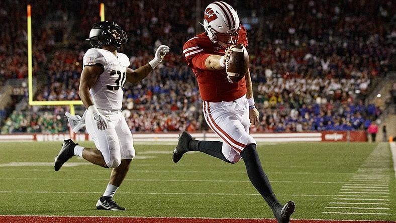 Oct 16, 2021; Madison, Wisconsin, USA;  Wisconsin Badgers quarterback Graham Mertz (5) rushes for a touchdown in front of Army Black Knights linebacker Daryan McDonald (30) during the second quarter at Camp Randall Stadium. Mandatory Credit: Jeff Hanisch-USA TODAY Sports