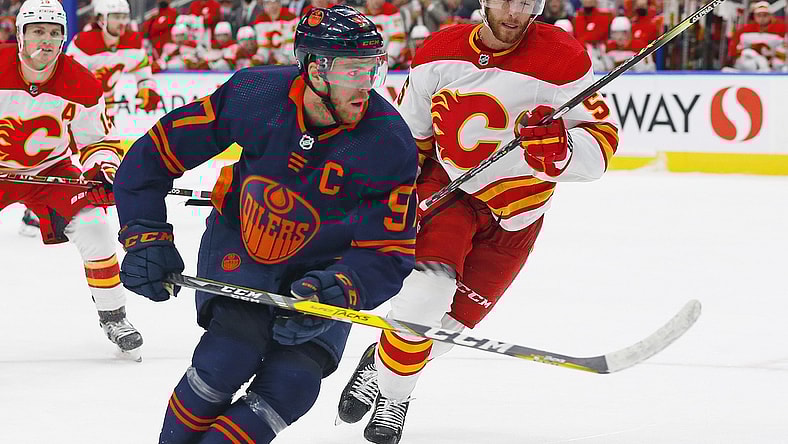 Oct 16, 2021; Edmonton, Alberta, CAN; Edmonton Oilers forward Connor McDavid (97) and Calgary Flames defensemen Noah Hanifin (55) chase a loose puck during the third period at Rogers Place. Mandatory Credit: Perry Nelson-USA TODAY Sports