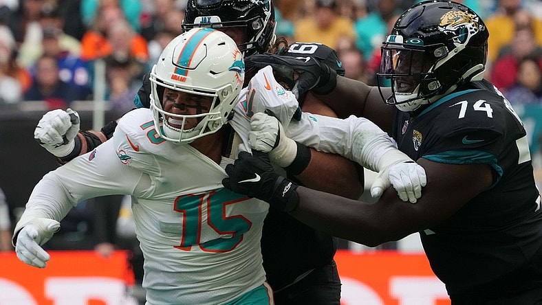 Oct 17, 2021; London, England, United Kingdom; Miami Dolphins outside linebacker Jaelan Phillips (15) is defended by Jacksonville Jaguars guard Andrew Norwell (68) and offensive tackle Cam Robinson (74) in the first half during an NFL International Series game at Tottenham Hotspur Stadium. Mandatory Credit: Kirby Lee-USA TODAY Sports