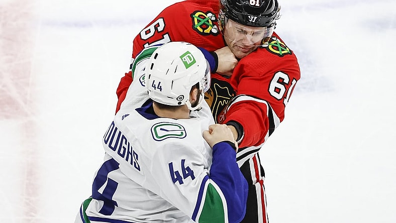 Oct 21, 2021; Chicago, Illinois, USA; Vancouver Canucks defenseman Kyle Burroughs (44) fights with Chicago Blackhawks defenseman Riley Stillman (61) during the first period at United Center. Mandatory Credit: Kamil Krzaczynski-USA TODAY Sports