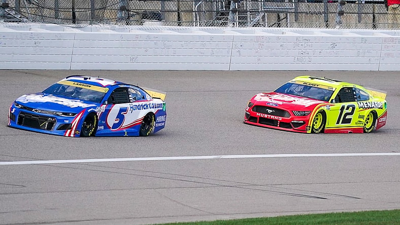 Oct 24, 2021; Kansas City, Kansas, USA; NASCAR Cup Series driver Kyle Larson (5) and driver Ryan Blaney (12) go into turn one near the start of the Hollywood Casino 400 at Kansas Speedway. Mandatory Credit: Denny Medley-USA TODAY Sports