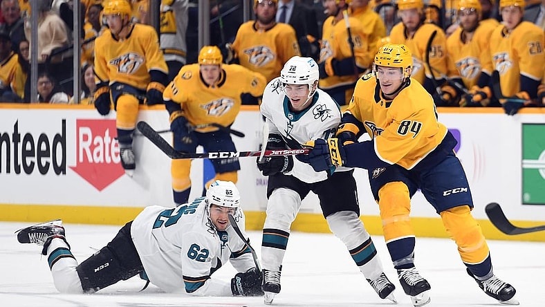 Oct 26, 2021; Nashville, Tennessee, USA; Nashville Predators left wing Tanner Jeannot (84) battles for a loose puck with San Jose Sharks right wing Kevin Labanc (62) and San Jose Sharks left wing William Eklund (72) during the first period at Bridgestone Arena. Mandatory Credit: Christopher Hanewinckel-USA TODAY Sports