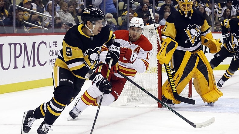 Oct 28, 2021; Pittsburgh, Pennsylvania, USA;  Pittsburgh Penguins center Evan Rodrigues (9) moves the puck against Calgary Flames center Mikael Backlund (11) during the first period at PPG Paints Arena. Mandatory Credit: Charles LeClaire-USA TODAY Sports