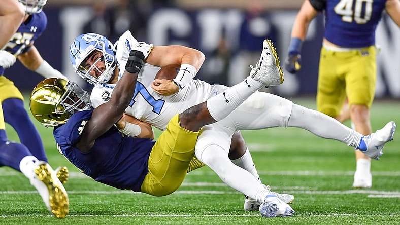 Oct 30, 2021; South Bend, Indiana, USA; North Carolina Tar Heels quarterback Sam Howell (7) is tackled by Notre Dame Fighting Irish defensive lineman Nana Osafo-Mensah (31) in the first quarter at Notre Dame Stadium. Mandatory Credit: Matt Cashore-USA TODAY Sports