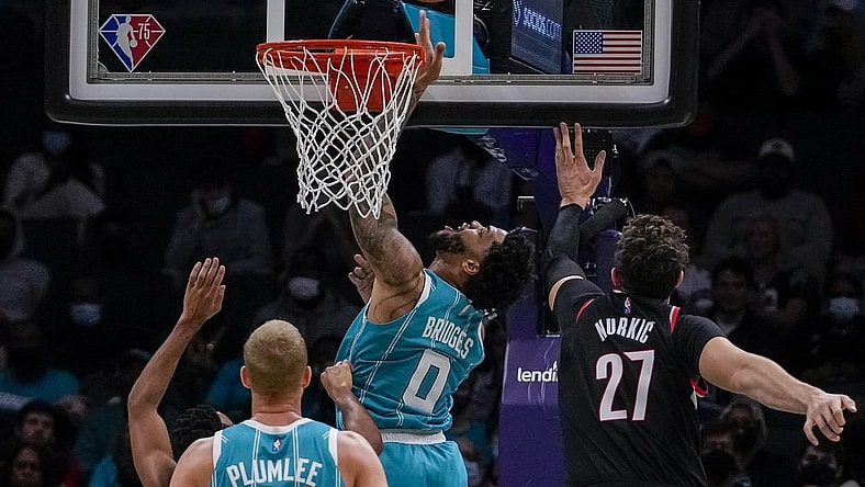 Oct 31, 2021; Charlotte, North Carolina, USA; Charlotte Hornets forward Miles Bridges (0) makes a reverse layup past Portland Trail Blazers center Jusuf Nurkic (27) during the second quarter at Spectrum Center. Mandatory Credit: Jim Dedmon-USA TODAY Sports